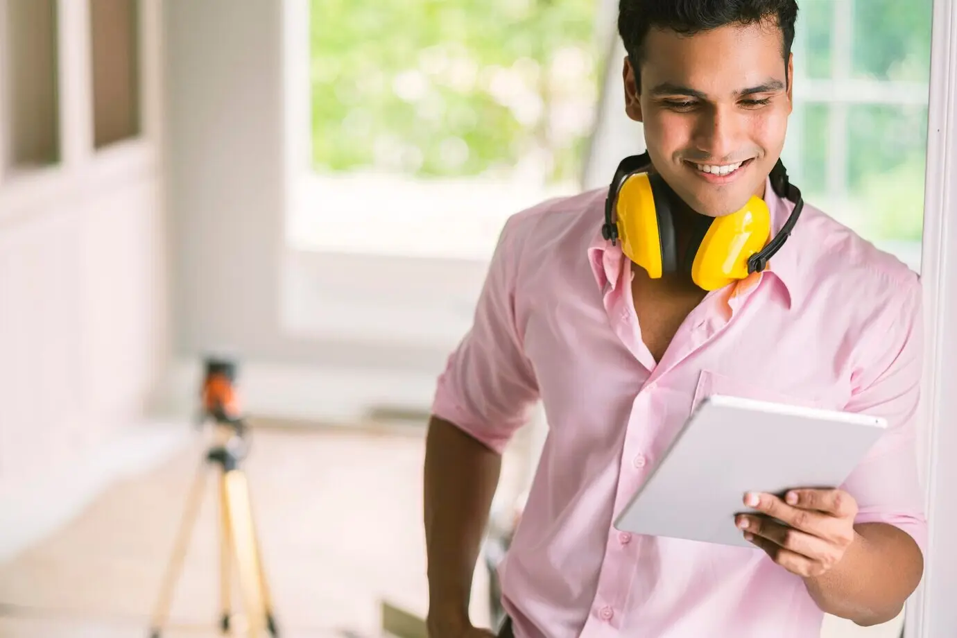 Cleverer indischer Schreiner als Auftragnehmer mit Schutzbrille und Kopfhörer prüft die weiße Deckenleiste für ein Hauskonzept der Innenraumdekoration.